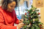 Female decorating a small tree in a hospital room