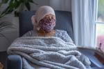 Masked female cancer patient in bed 