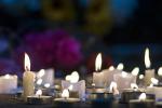 candles flicker outside at night in a makeshift memorial