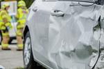Close up on a car crashed with fireman in background 