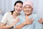 An Asian woman wearing a head scarf due to cancer and her daughter sit in a bed
