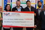 A group of five people holds a large plastic check for $1.4 million dollars for a UC Davis MIND Institute research program. 