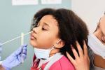 A young girl gets a nasal swab for a COVID-19 test at the doctor’s office with her mom. 
