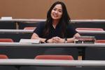 A young woman sits in a lecture hall next to medical school textbooks