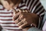 A close-up photo shows a caregiver holding the hand of a senior woman in a striped shirt.