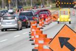 A move left sign and a digital flashing arrow with traffic cones advises cars on freeway.   