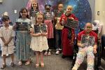 8 children stand holding certificates