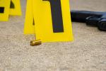 Gun shell casing, yellow evidence tags and a gun at crime scene.