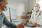 Middle aged family doctor is talking with young male patient during consultation in a Health Clinic. 