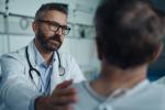 Doctor leaning forward with hand on patient's shoulder.