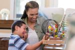 A young boy plays with an adult on an abacus-type toy.