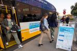 Woman exiting the back of a Sacramento Regional Transit bus as others walk away from the bus. 