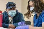 Worker in baseball cap Antonio González, 37, gets his COVID-19 booster shot in the office of Pamukey Yolo Vineyard near Esparto