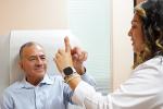 A man in a medical chair touches his finger to a physician’s finger as part of a neurological exam.