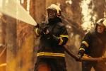 Two firefighters holding a hose to put out a forest fire