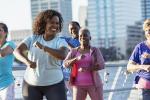 A group of smiling senior adults exercise outdoors in a city.