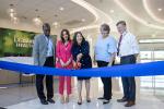 adults stand with a large pair of scissors to cut a ribbon in a health care facility