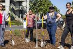 four adults stand outside holding shovels and rakes in a garden on the UC Davis Health campus 