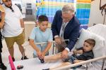 Four adults stand around a hospital bed where a young boy is connected to an intravenous line delivering life-altering therapy