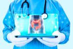 Doctor wearing a stethoscope holds a tablet projecting the human large intestine on the screen.