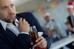 Adult businessman holding his chest in pain while being at an office holiday party, holding a drink.