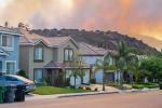 Row of residential houses along street with hill in the background on fire