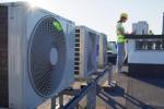 Construction worker stands near air conditioning systems.