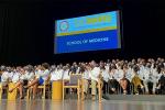 The 133 new medical students in white lab coats sit on the stage at Mondavi Center during their induction ceremony