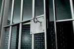 A jail cell with iron bars and a key in the locking mechanism with the door open.