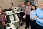 A group of people stand in a room next to a machine.