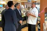 Three men stand together in a cafeteria.