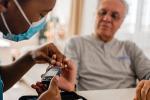 Nurse pricking finger of patient to check their blood sugar