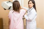 The female doctor is looking at computer while woman is having a mammogram 