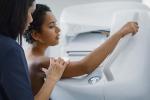 Female health professional guiding woman in correct stance for a mammogram