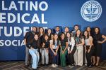 A group of 15 medical students stand before a large blue background that states, “The Latino Medical Student Association.”