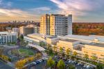 Aerial view of UC Davis Medical Center lit gold by the sun setting to the left side of the building.