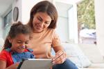 mother and daughter on a couch looking at a tablet together