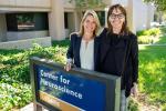 Two women stand behind a sign for the UC Davis Center for Neuroscience
