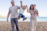 Man and woman standing on beach holding two boys in the air. 