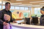 Parent and child stand at counter, while a person checks them in.