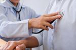 A doctor examines a patient with a stethoscope on the patient’s chest.