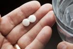 Pills in a hand and a glass of water