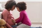 Daughter touching mother's pregnant belly