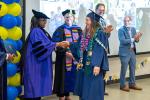 A redwood seed scholar walks across the room shaking hands with a line of people and getting a diploma