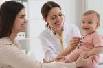 Female doctor examining baby while female looks on