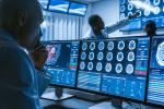 doctor in front of computer screen with brain scans 