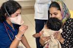 A physician with a mask on talks to a baby and mother