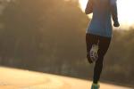 Young fitness woman runner running on a road at sunrise