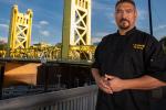 Santana Diaz wearing black chef coat standing in front of golden bridge