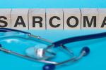 wooden blocks spelling sarcoma with a stethescope on a blue background